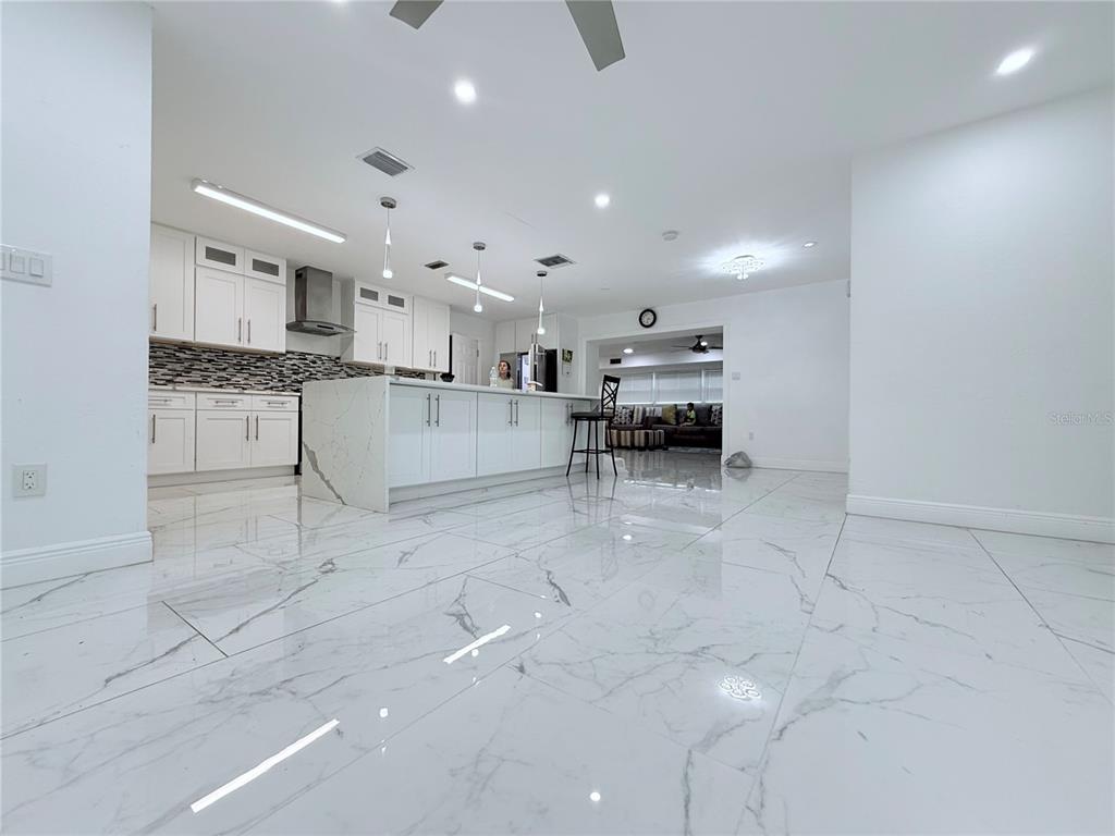 A kitchen island with white cabinets and a marble-patterned countertop sits in a bright room — 1557 ROBINSON DRIVE N, ST PETERSBURG, FL