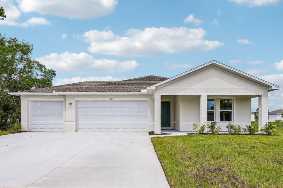 A single-story house with a three-car garage, light stucco exterior, and a covered front porch — 16107 MINORCA DRIVE, PUNTA GORDA, FL