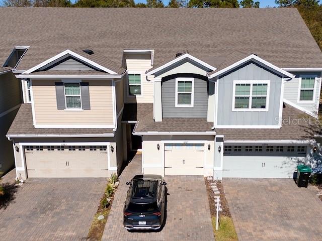 An aerial view shows three attached townhomes with garages and a car parked in front — 6989 TUSSILAGO WAY, ORLANDO, FL