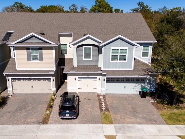 An aerial view shows the front exterior of a three-unit townhouse complex with paved driveways — 6989 TUSSILAGO WAY, ORLANDO, FL