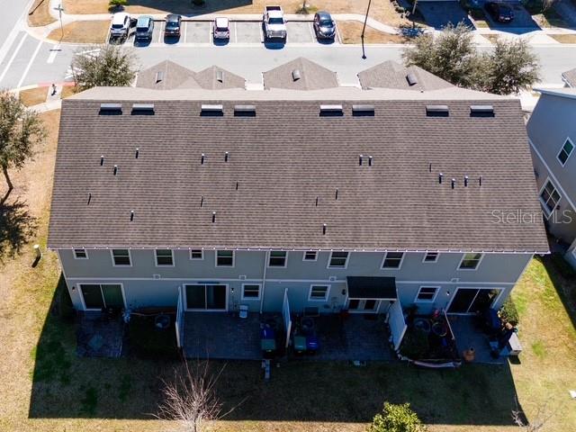An aerial view shows the shingled roof and rear patios of a multi-unit townhouse building — 6989 TUSSILAGO WAY, ORLANDO, FL