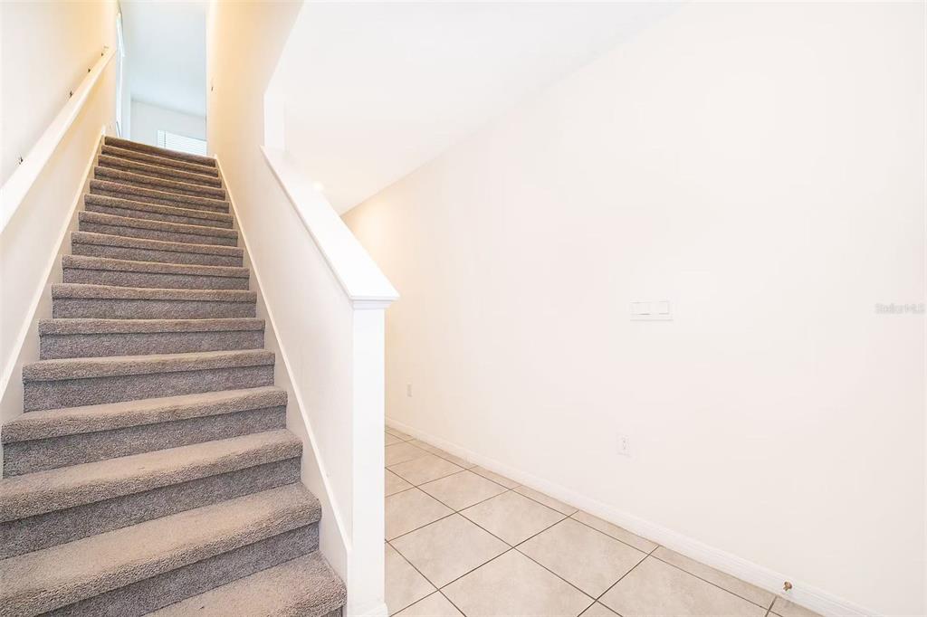 A carpeted staircase leads to an upper level next to a tiled entryway — 30915 PENNY SURF LOOP, WESLEY CHAPEL, FL