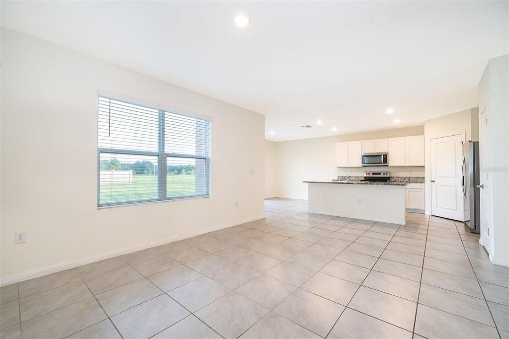 An open-concept kitchen and living area with tile flooring, white cabinets, and a large window — 30915 PENNY SURF LOOP, WESLEY CHAPEL, FL