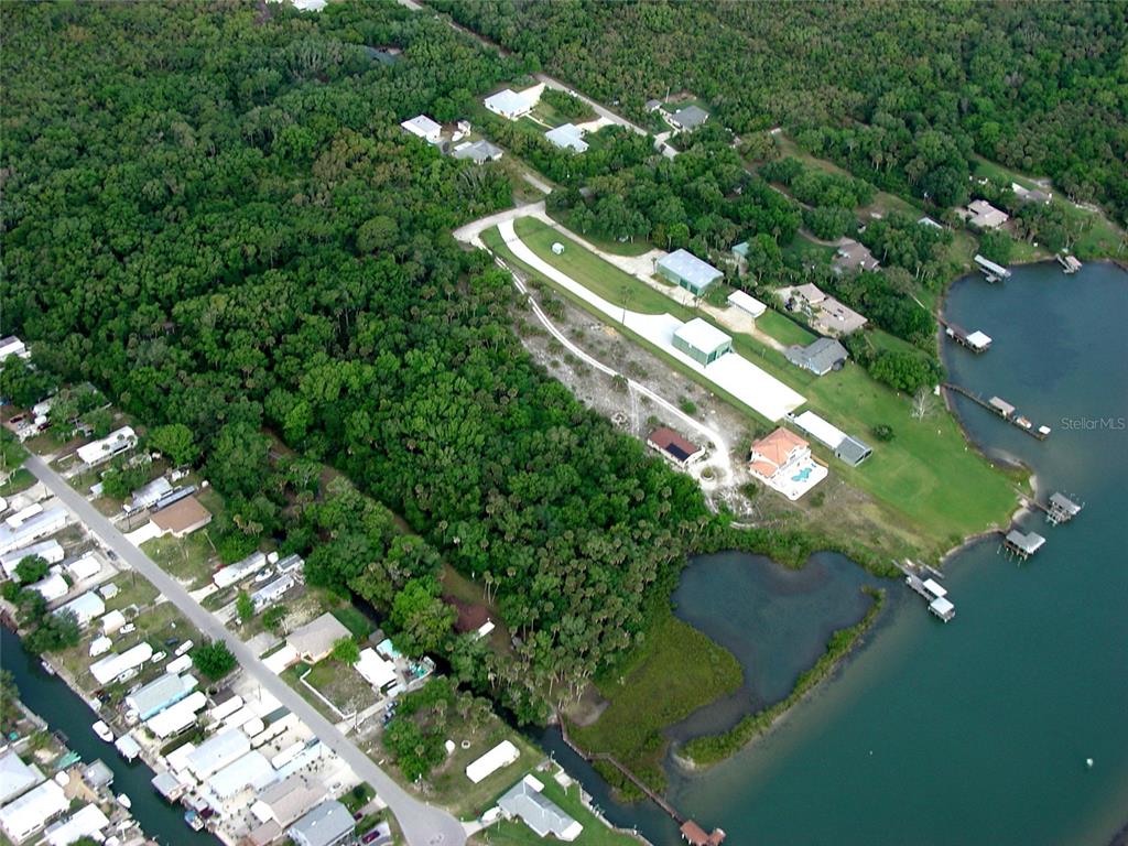 An aerial view shows a residential property with a long driveway, outbuildings, and waterfront access — MYRTLE STREET, EDGEWATER, FL