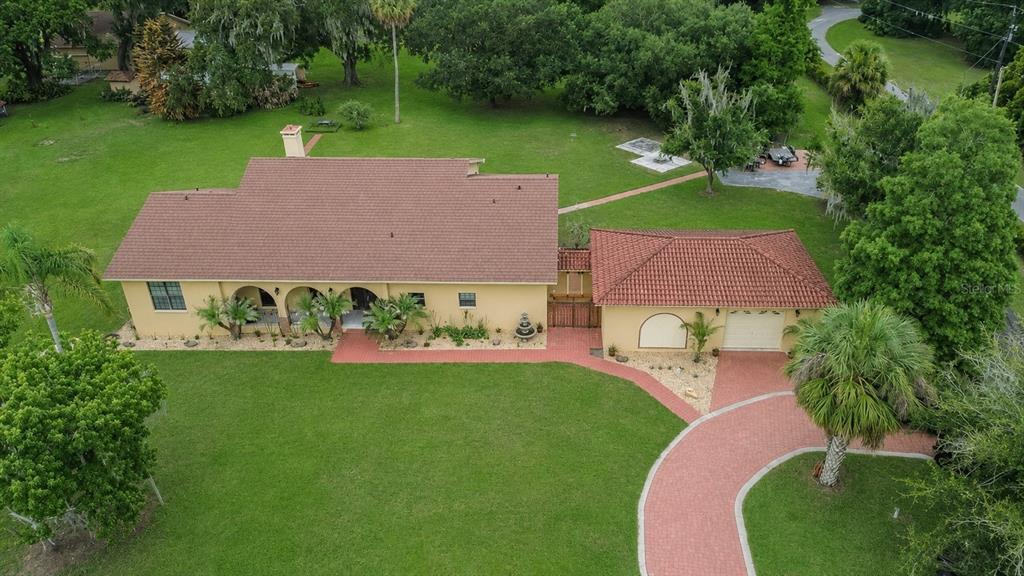 A black metal gate with a custom monogram stands between two tan stucco pillars — 4020 N WILDER ROAD, PLANT CITY, FL