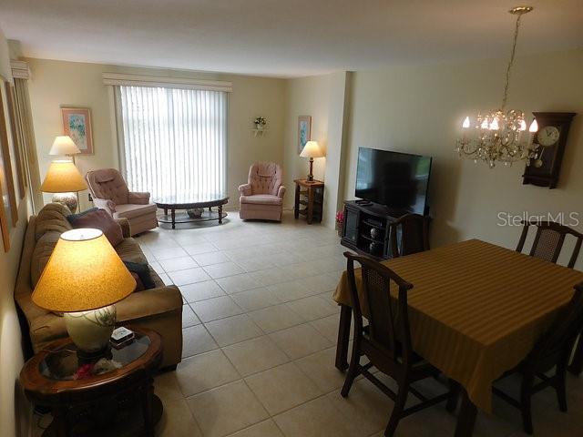 A living and dining room area features tile flooring, a chandelier, and neutral wall colors — 716 GRANADA AVENUE UNIT 302, VENICE, FL