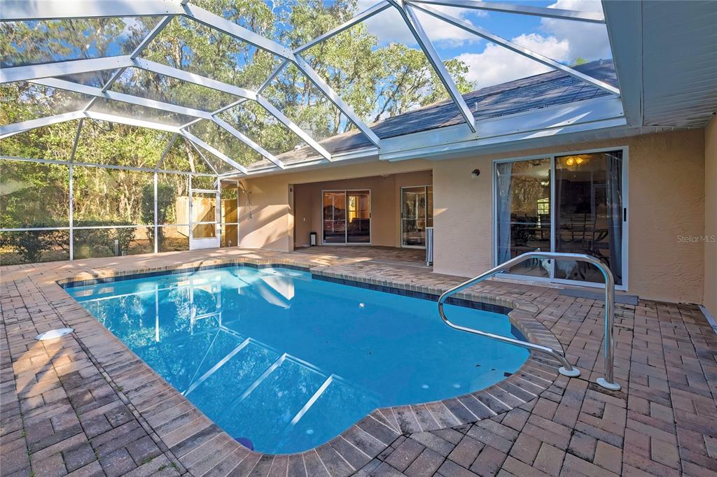 A screened-in swimming pool with a brick paver deck and a covered patio area — 340 E SAVOY STREET, LECANTO, FL
