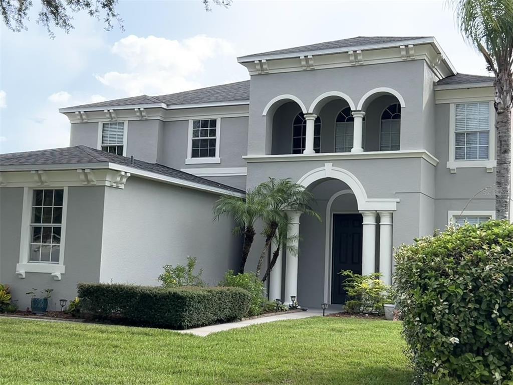 A two-story gray house features a covered entryway with columns and an upper-level arched balcony — 4830 STONE ACRES CIRCLE, ST CLOUD, FL