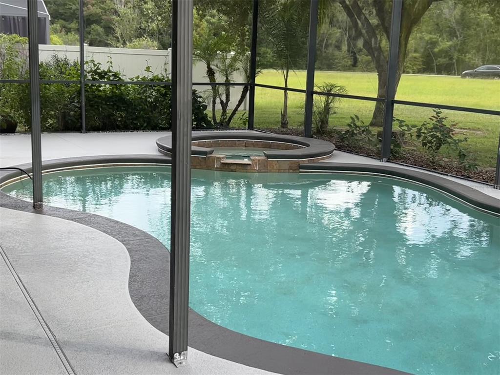 A swimming pool with an integrated spa is enclosed by a screened lanai — 4830 STONE ACRES CIRCLE, ST CLOUD, FL
