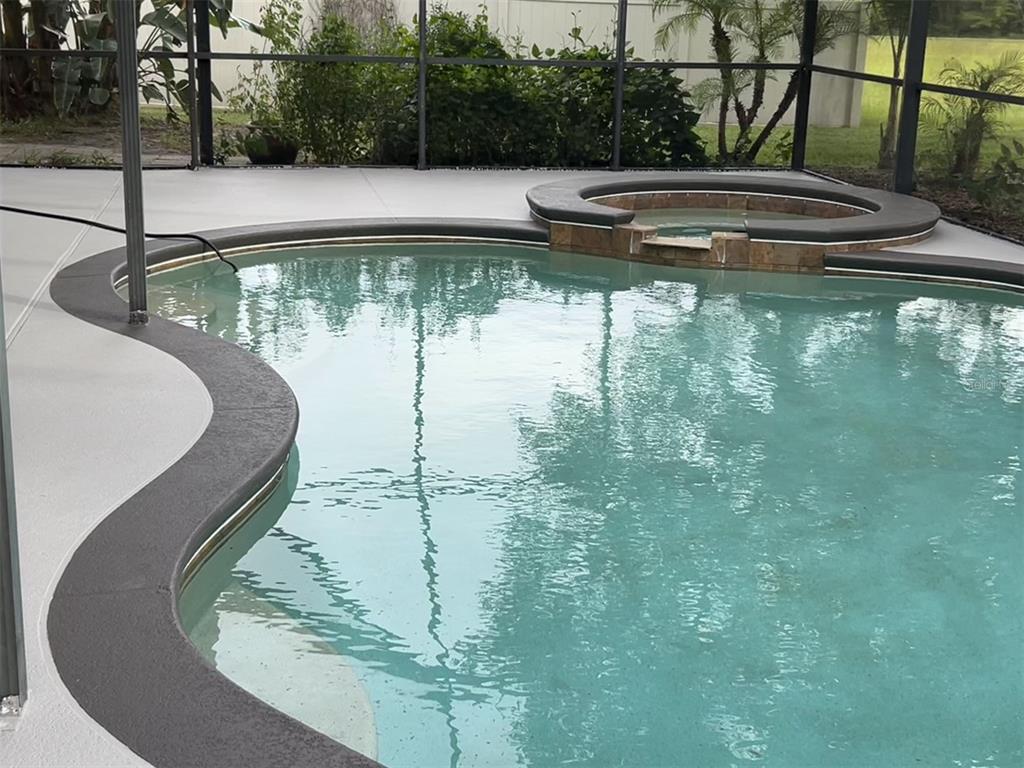 A swimming pool with an attached spa and a screened-in patio area — 4830 STONE ACRES CIRCLE, ST CLOUD, FL