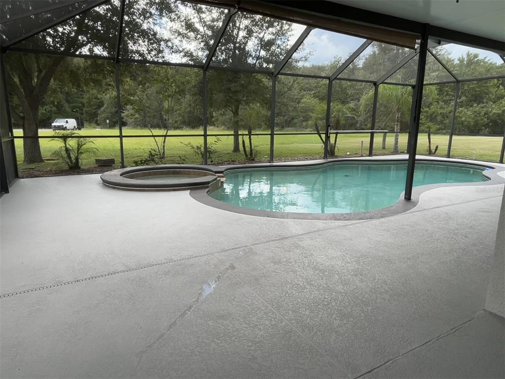 A screened-in patio features a swimming pool, a raised spa, and a gray concrete deck — 4830 STONE ACRES CIRCLE, ST CLOUD, FL