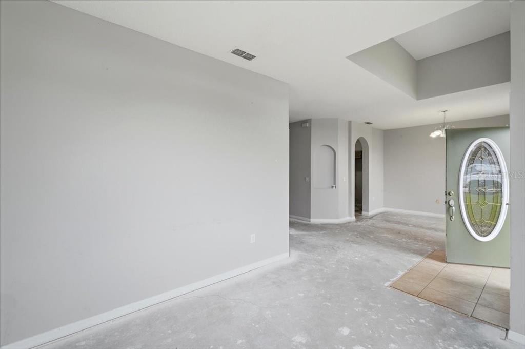 An empty room with light gray walls, concrete flooring, and an open front door — 153 OAK CROSSING BOULEVARD, AUBURNDALE, FL