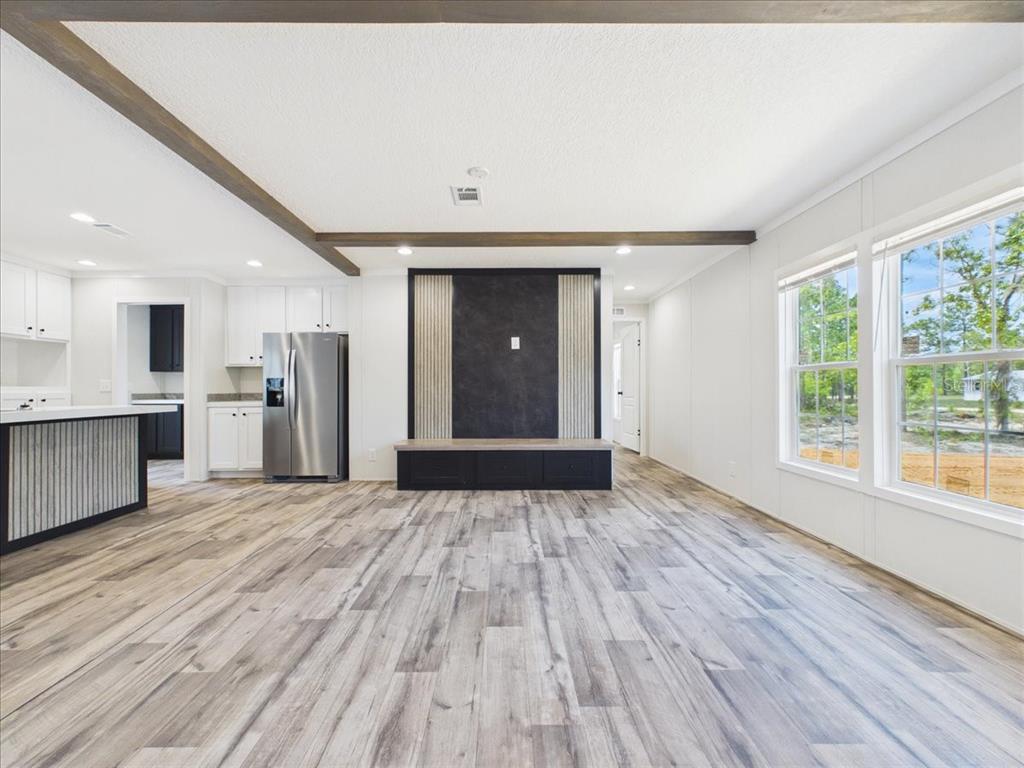 A living room features a black media wall, wood ceiling beams, and an open kitchen — 137 BEULAH DRIVE, HAWTHORNE, FL