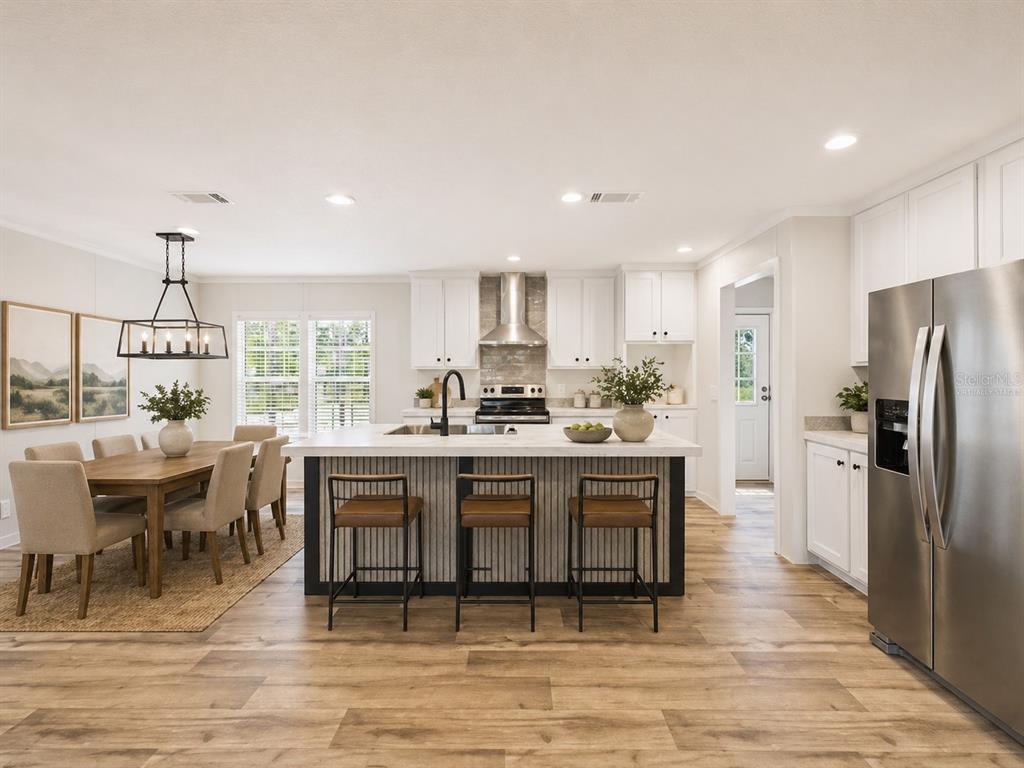 An open-concept living area features wood-look flooring, a dark accent wall, and white kitchen cabinets — 137 BEULAH DRIVE, HAWTHORNE, FL