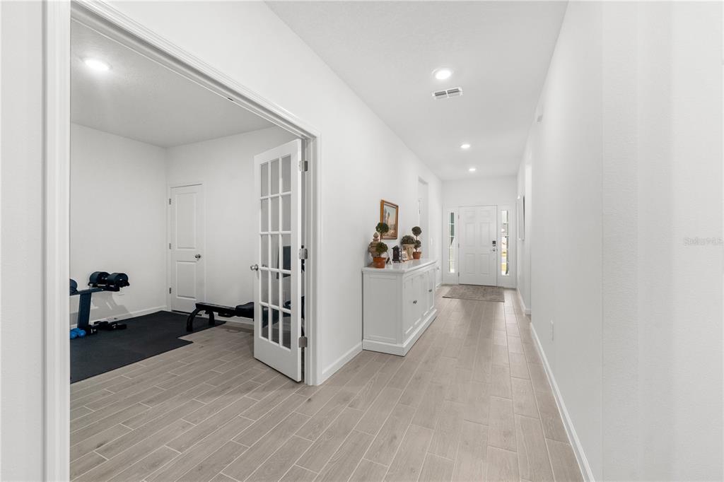 A living room features a large sectional sofa, a wooden hutch, and tile flooring — 13941 NW CONVERGENCE BOULEVARD, ALACHUA, FL