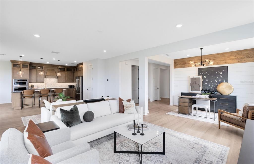 An open-concept living room features a white sofa, a home office area, and a kitchen — 1538 VALIER POINT, ZEPHYRHILLS, FL