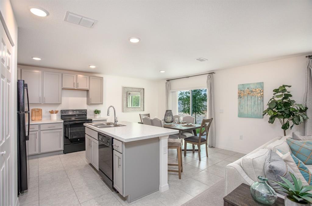 A kitchen with gray cabinets, a central island, and an adjacent dining area with sliding doors — 3104 MANDRELL AVENUE, SPRING HILL, FL