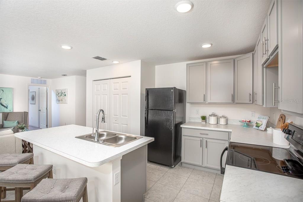 A kitchen with a central island, grey cabinets, white countertops, and a black refrigerator — 3104 MANDRELL AVENUE, SPRING HILL, FL