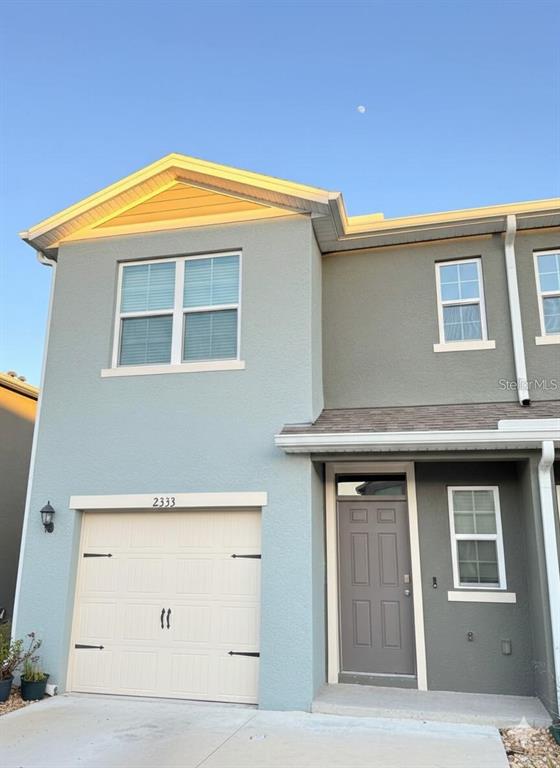 A two-story townhouse exterior features a light blue facade, a single-car garage, and a gray door — 2333 PENGUIN BOULEVARD, DAVENPORT, FL