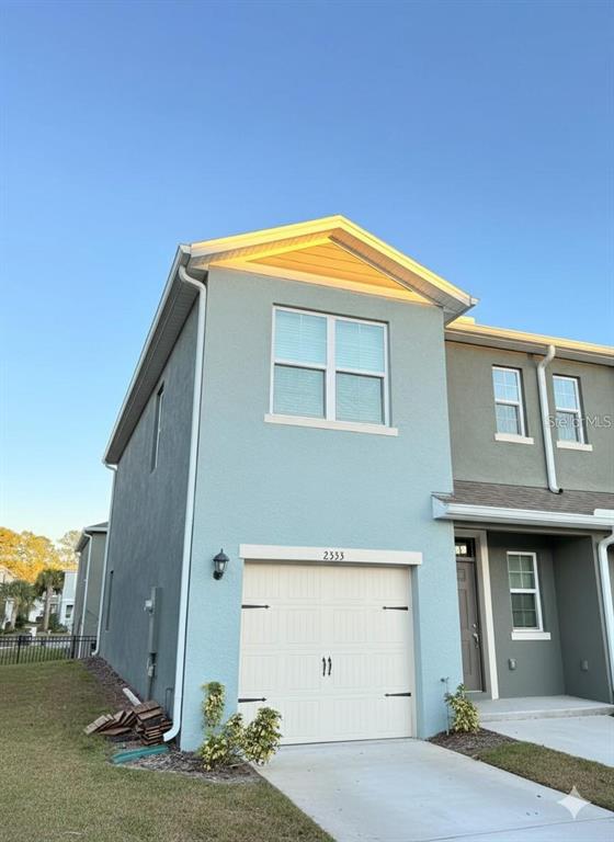 A two-story light blue townhouse with a single-car garage and a concrete driveway — 2333 PENGUIN BOULEVARD, DAVENPORT, FL