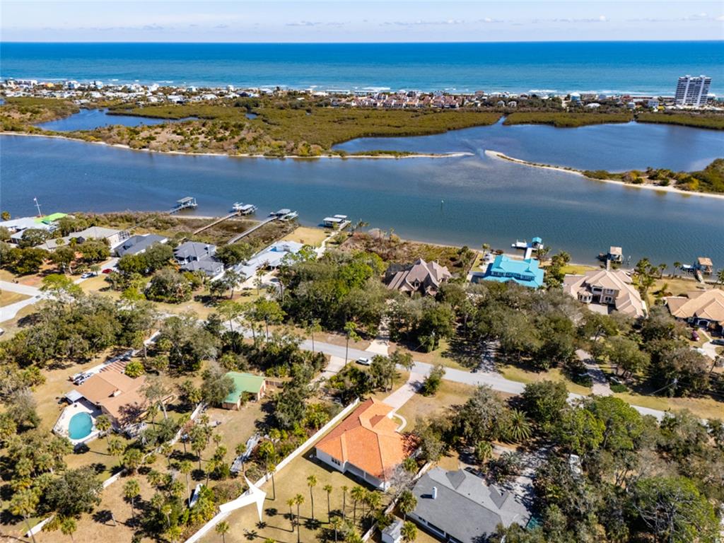 An aerial view shows a residential neighborhood with houses, trees, and a nearby coastal waterway — 1591 LAMBERT AVENUE, FLAGLER BEACH, FL