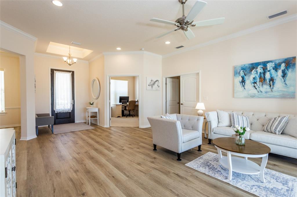 A living room with light wood flooring, a white sofa, and an adjacent home office — 1591 LAMBERT AVENUE, FLAGLER BEACH, FL