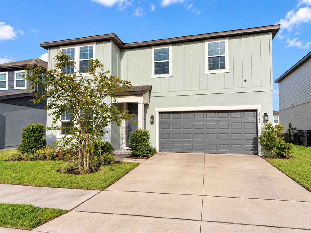 An open-concept living area features light wood-look flooring, white walls, and a kitchen island — 2077 DERWENT DRIVE, DAVENPORT, FL