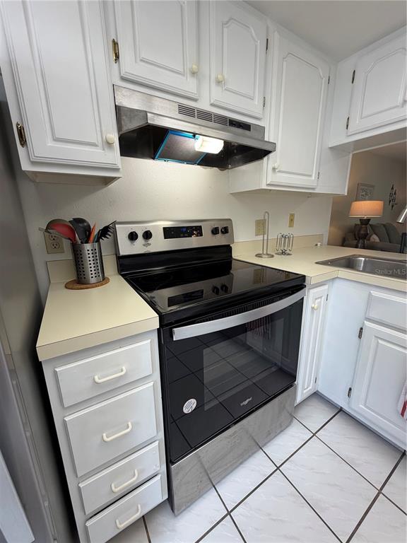 A kitchen features white cabinets, a stainless steel range, and a tiled floor — 204 WINDWARD PLACE UNIT 36, OLDSMAR, FL