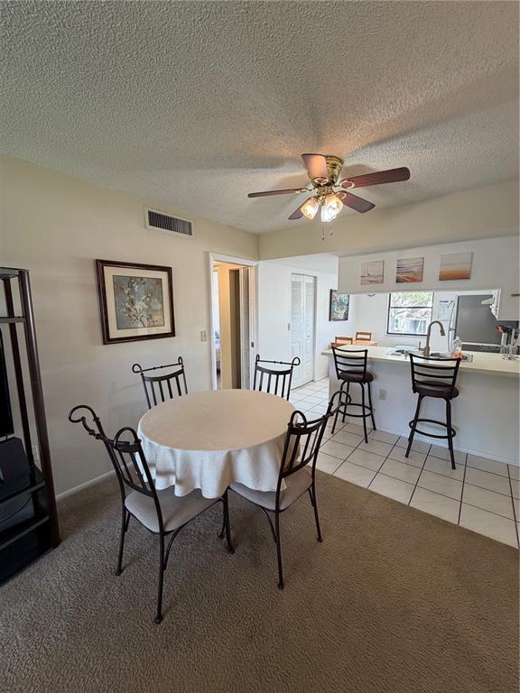 A dining area with a round table and chairs sits adjacent to a kitchen counter — 204 WINDWARD PLACE UNIT 36, OLDSMAR, FL