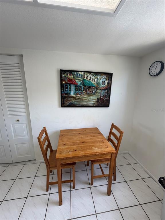 A dining area features a wooden table with two chairs, a wall painting, and tiled floors — 204 WINDWARD PLACE UNIT 36, OLDSMAR, FL