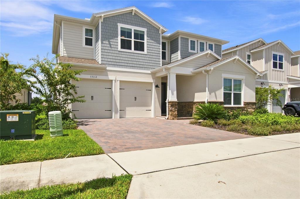 A two-story suburban house features a two-car garage, stone accents, and a paved driveway — 13112 DENDY WAY, WINTER GARDEN, FL