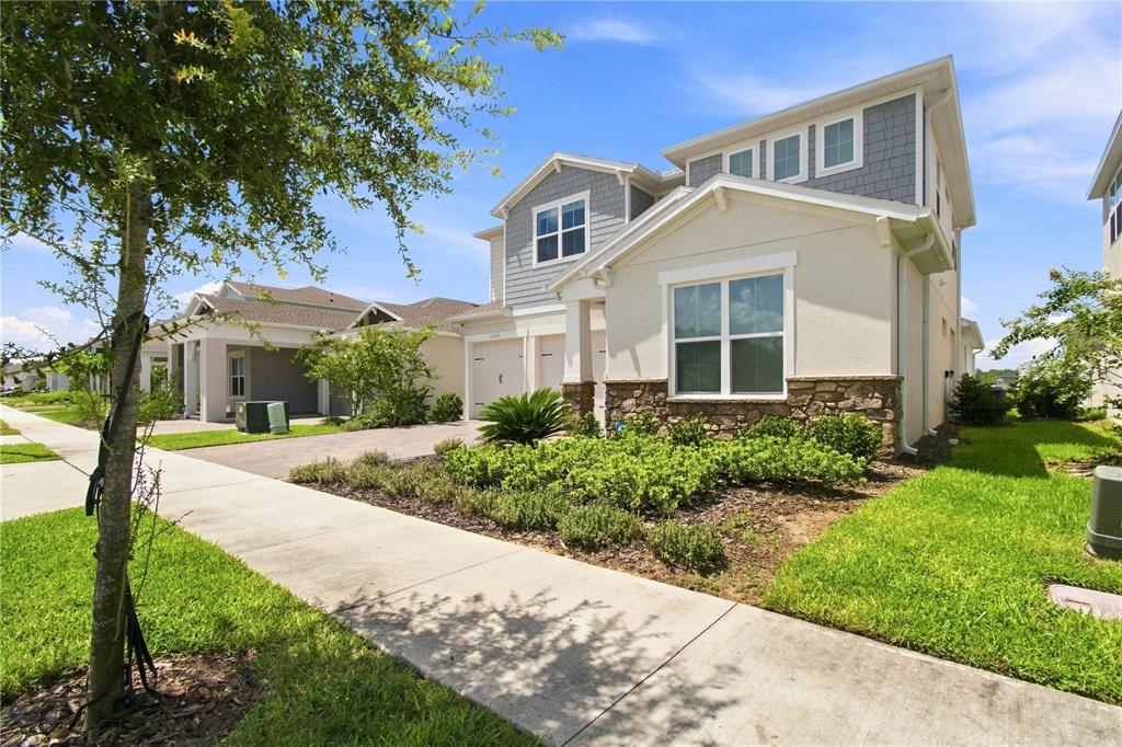 A two-story suburban house with a stone-accented facade, gray siding, and a concrete driveway — 13112 DENDY WAY, WINTER GARDEN, FL