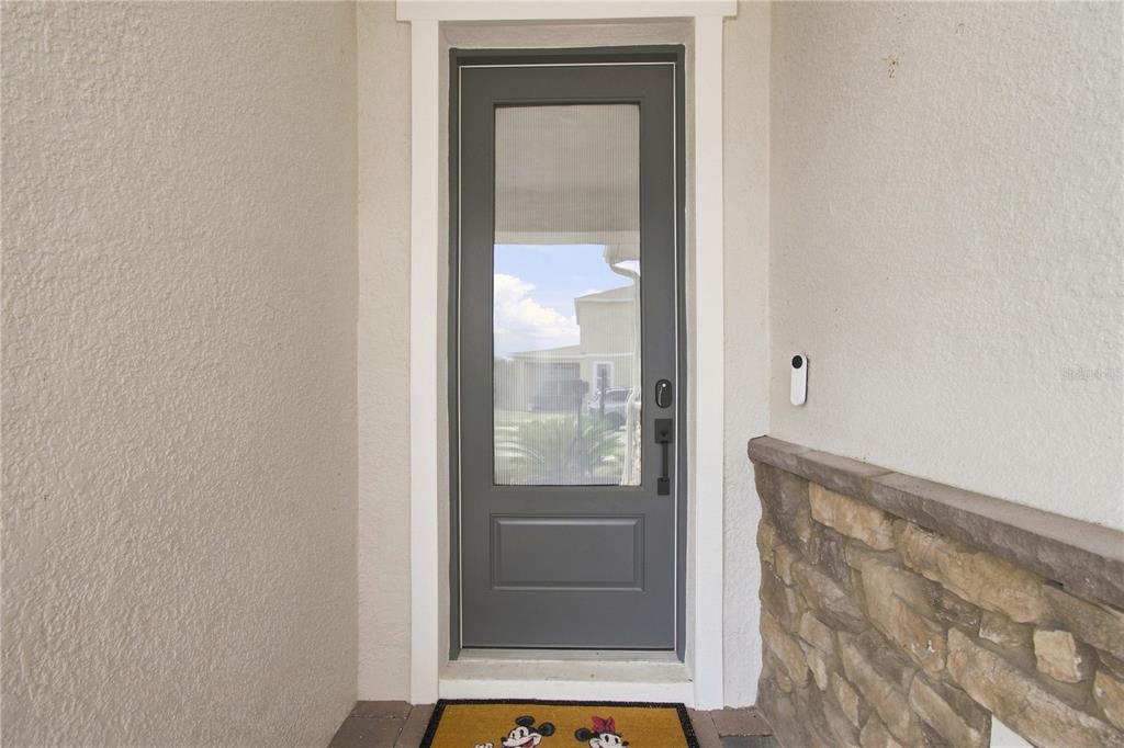 A gray front door with a glass panel is set in a stucco and stone entryway — 13112 DENDY WAY, WINTER GARDEN, FL