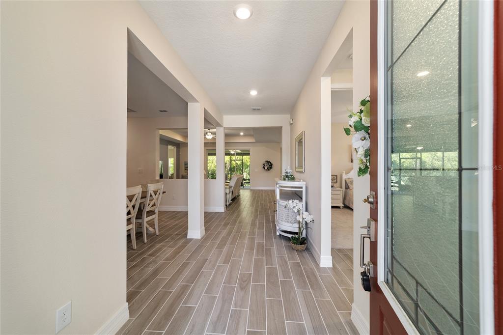 A bright entryway with wood-look tile flooring leads into an open-concept living area — 1129 SE 42ND ROAD, OCALA, FL