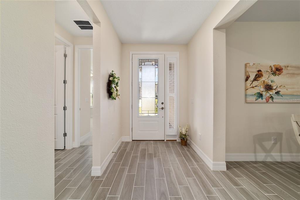 An entryway with gray wood-look tile flooring, a white front door, and neutral walls — 1129 SE 42ND ROAD, OCALA, FL