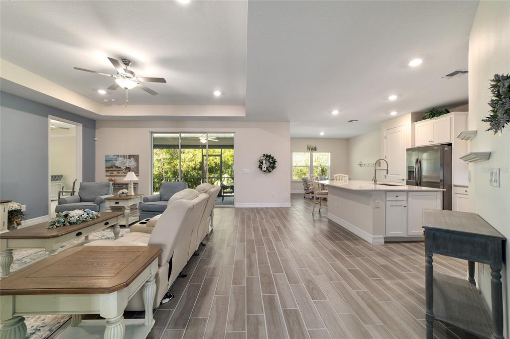 An open-concept living room and kitchen feature wood-look tile flooring and a sliding glass door — 1129 SE 42ND ROAD, OCALA, FL