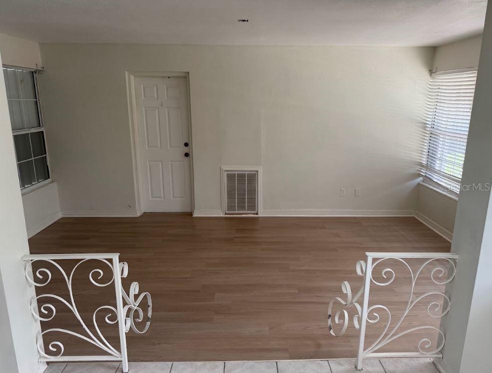 An interior room features light wood-look flooring, a white door, and decorative white metal railings — 3776 23RD AVENUE N, ST PETERSBURG, FL