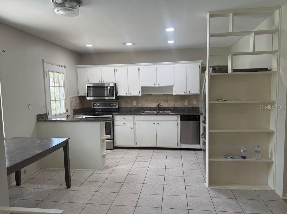 A kitchen with white cabinets, granite countertops, stainless steel appliances, and light-colored tile flooring — 3776 23RD AVENUE N, ST PETERSBURG, FL