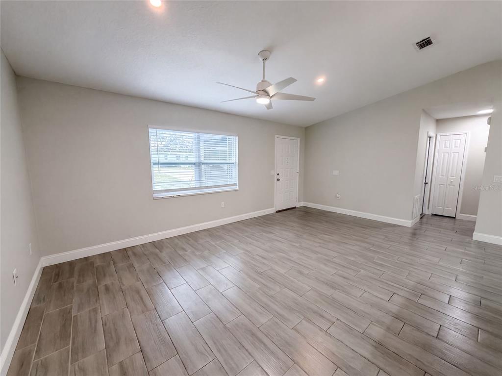 An empty room features light gray walls, wood-look tile flooring, a ceiling fan, and a window — 8165 RIDGE ROAD, WEEKI WACHEE, FL