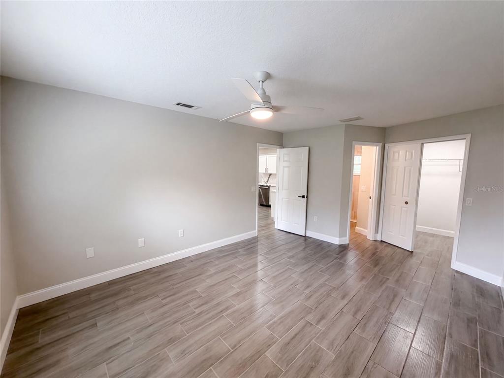 A bedroom features light gray walls, wood-look tile flooring, a ceiling fan, and two doorways — 8165 RIDGE ROAD, WEEKI WACHEE, FL