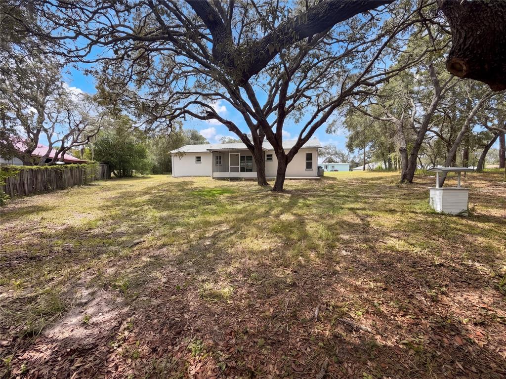 A white house sits in a large yard shaded by several mature oak trees — 8165 RIDGE ROAD, WEEKI WACHEE, FL