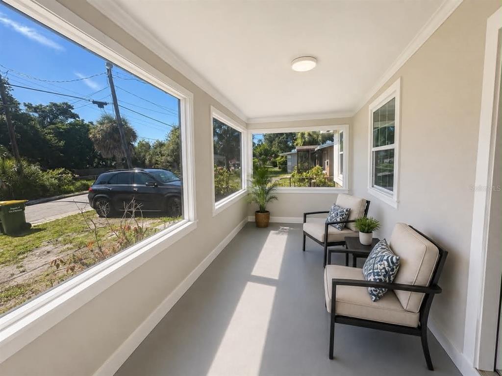 A sunroom with large windows, light gray flooring, and two chairs with patterned pillows — 2509 DIXIE AVENUE, SARASOTA, FL