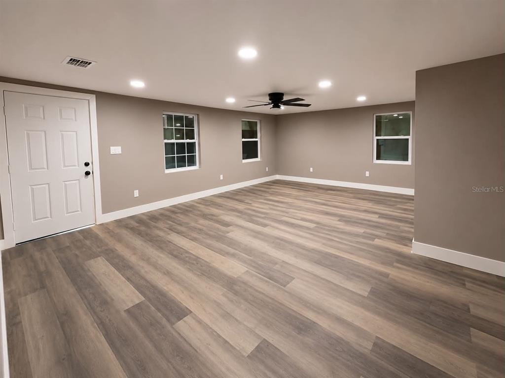 An empty room features light-colored wood-look flooring, gray walls, recessed lighting, and a ceiling fan — 2509 DIXIE AVENUE, SARASOTA, FL
