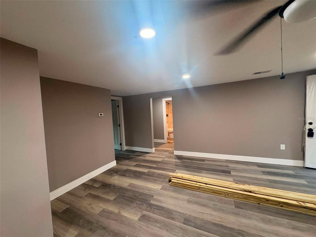 An empty room with gray walls, wood-look flooring, and a doorway leading to a bathroom — 2509 DIXIE AVENUE, SARASOTA, FL