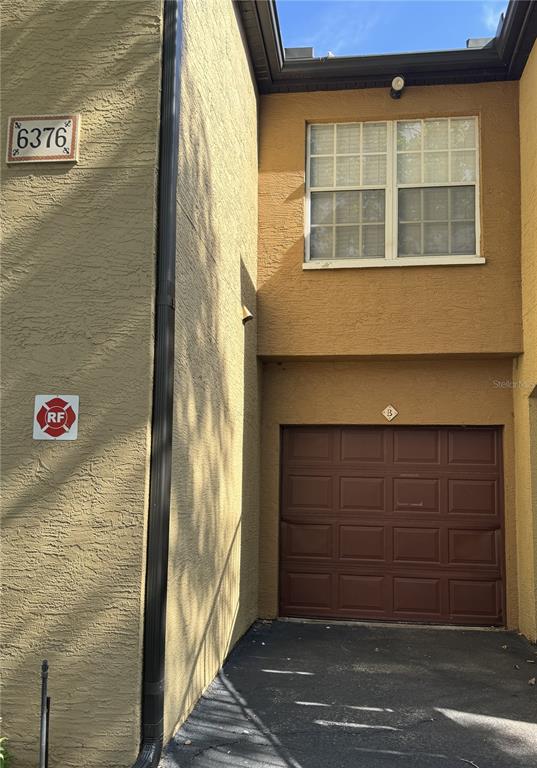 A tan stucco building exterior featuring a brown garage door and a second-story window — 6376 RALEIGH STREET UNIT 2001, ORLANDO, FL