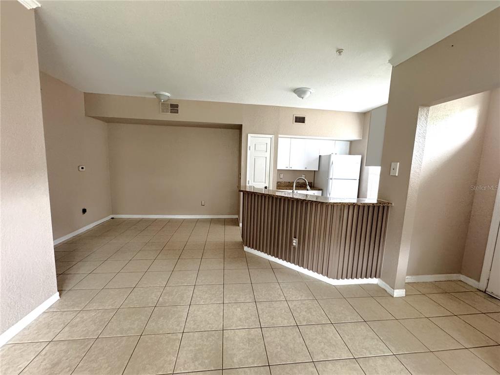 A kitchen features a breakfast bar, white cabinets, a refrigerator, and tile flooring — 6376 RALEIGH STREET UNIT 2001, ORLANDO, FL
