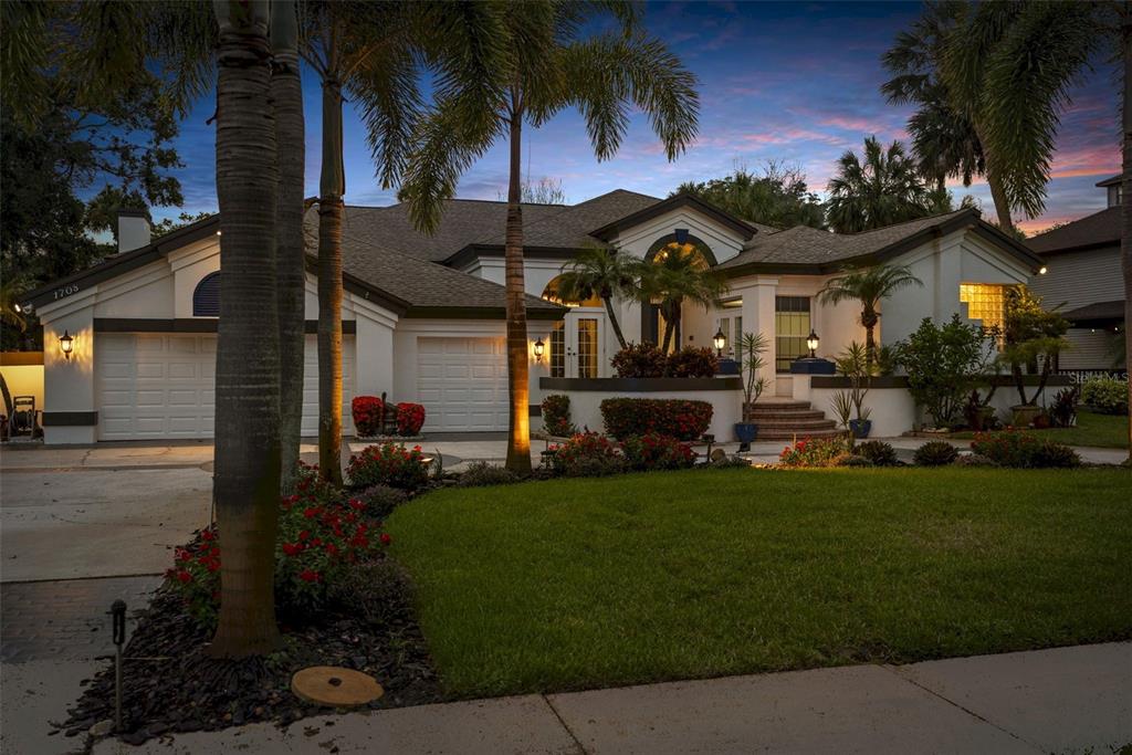 A single-story house with a white exterior, a multi-car garage, and palm trees at dusk — 1705 MEYERS COVE DRIVE, TARPON SPRINGS, FL