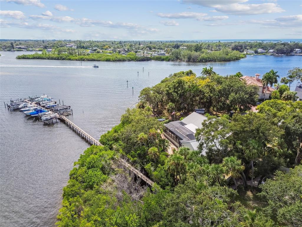 An aerial view shows a waterfront house with a long dock and multiple boats — 1705 MEYERS COVE DRIVE, TARPON SPRINGS, FL