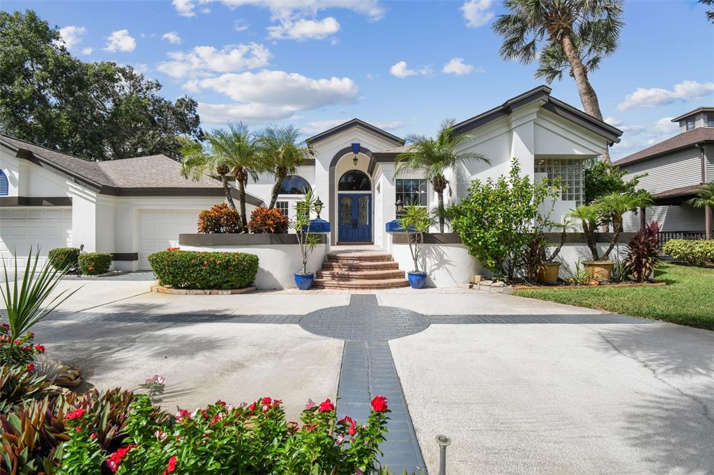 A white house with a blue front door and a circular driveway with brick accents — 1705 MEYERS COVE DRIVE, TARPON SPRINGS, FL
