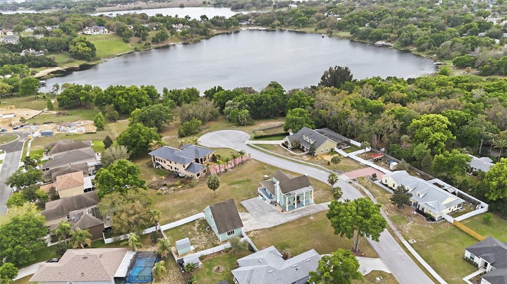 An aerial view shows several suburban houses situated near a large lake and trees — 835 BUTCH CASSIDY LANE, EUSTIS, FL